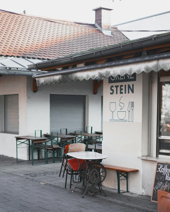 the outside of a restaurant with tables and chairs, a photo, by Kristian Zahrtmann, trending on unsplash, a ghetto in germany, stew, about to step on you, alvar aalto