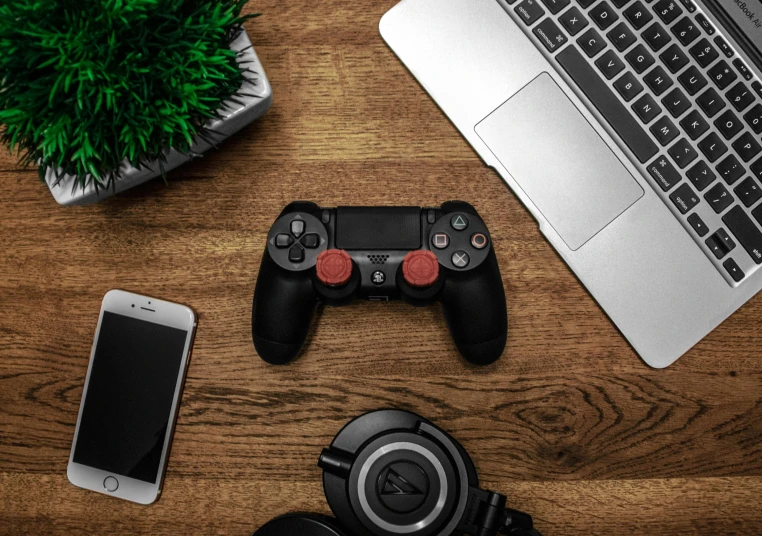 a laptop computer sitting on top of a wooden desk, a picture, holding controller, red and black colour scheme, curated collections, ps4