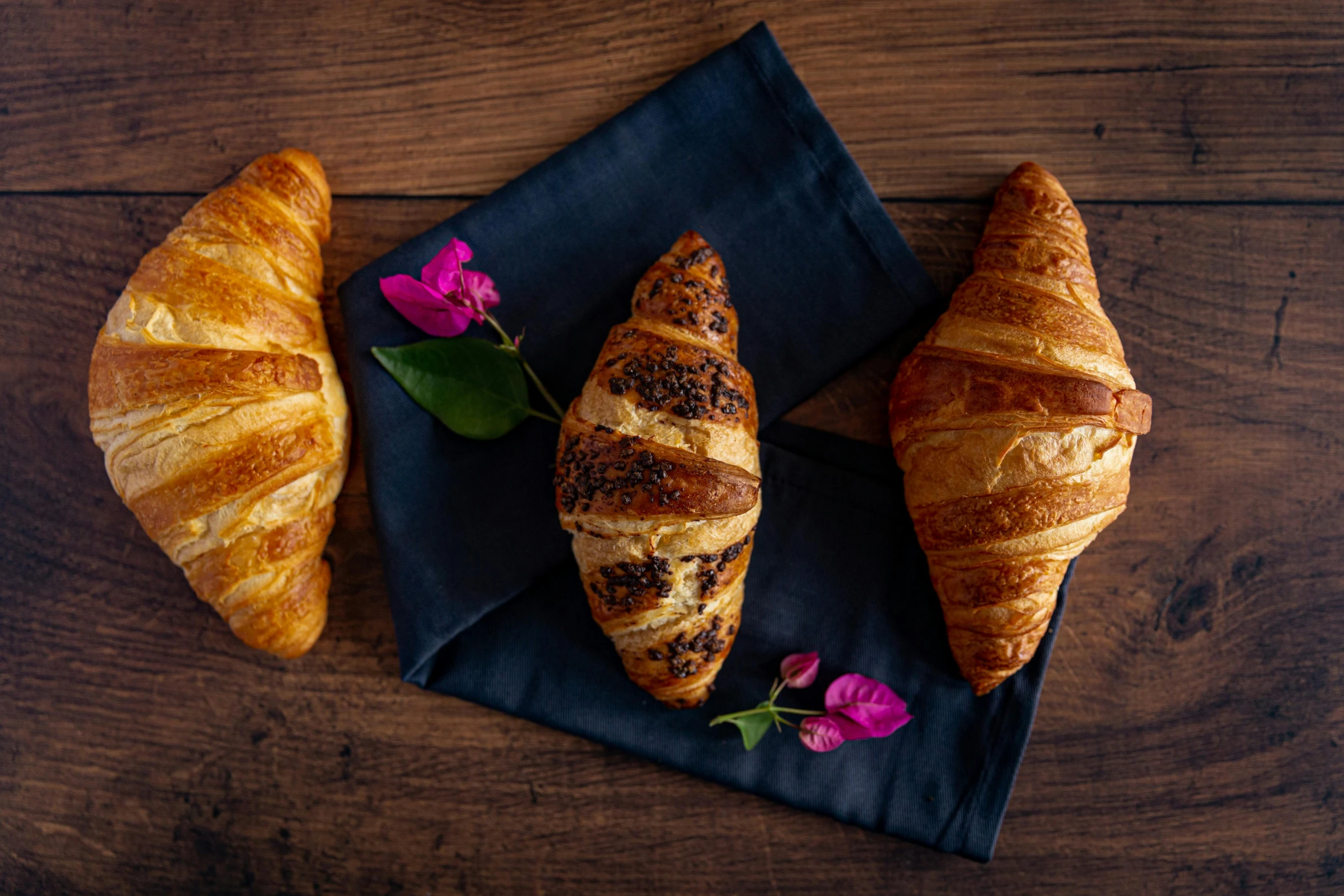 a couple of croissants sitting on top of a black napkin, a portrait, unsplash, fan favorite, various posed, 3 doors, botanicals