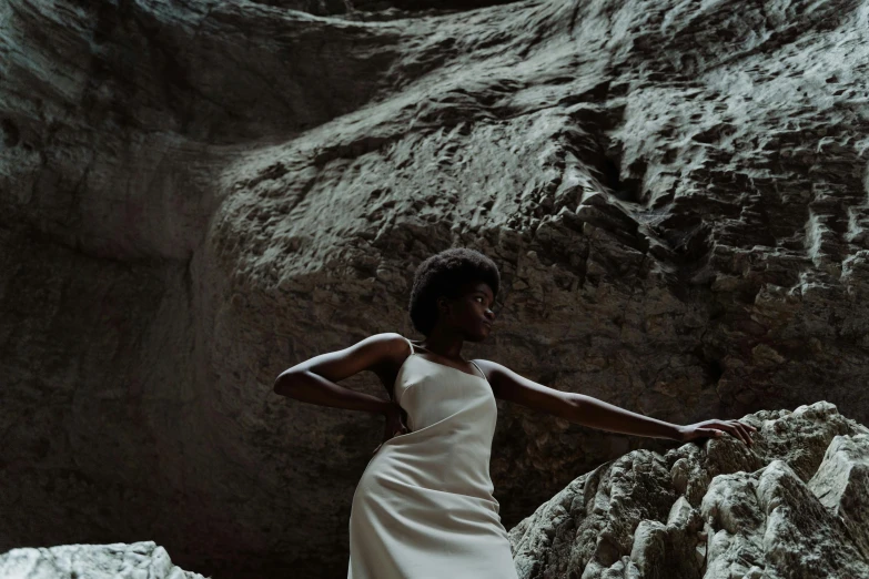 a woman in a white dress standing in a cave, by Emma Andijewska, unsplash contest winner, afrofuturism, photoshoot for skincare brand, thumbnail, ignant, other women dancing behind