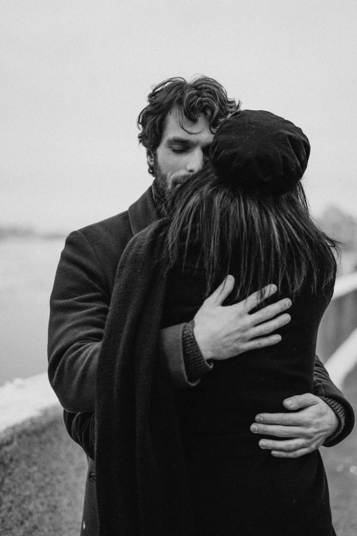 a black and white photo of a man hugging a woman, by Lucia Peka, pexels contest winner, winter, handsome man, instagram post, back