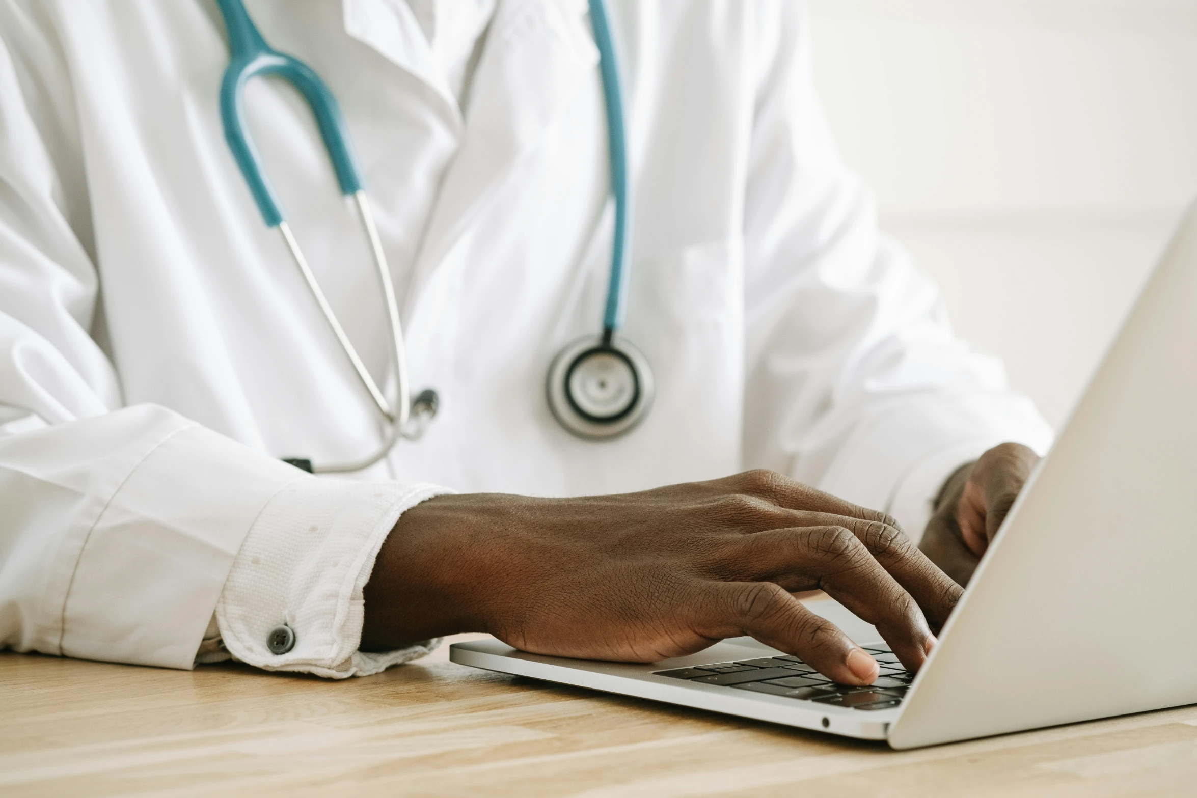 a close up of a person typing on a laptop, pexels, hurufiyya, with a stethoscope, brown, wearing a white hospital gown, coloured