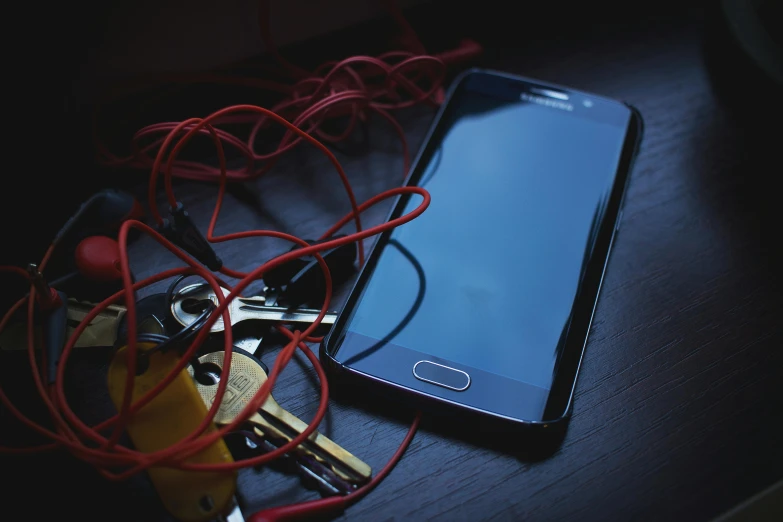 a cell phone sitting on top of a table next to a bunch of keys, pexels, red wires wrap around, avatar image, dark moody, security