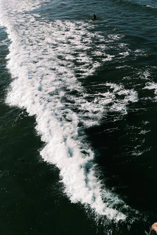 a person riding a surfboard on top of a body of water, zoomed in, water surrounds the ship, whirly, in a row