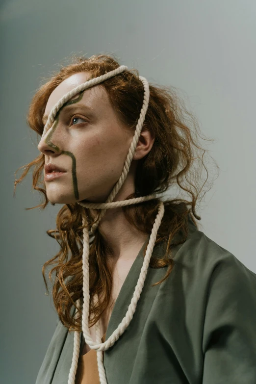 a woman with a rope around her head, an album cover, inspired by Anna Füssli, trending on pexels, renaissance, hr ginger, prosthetic makeup, androgynous male, muted green