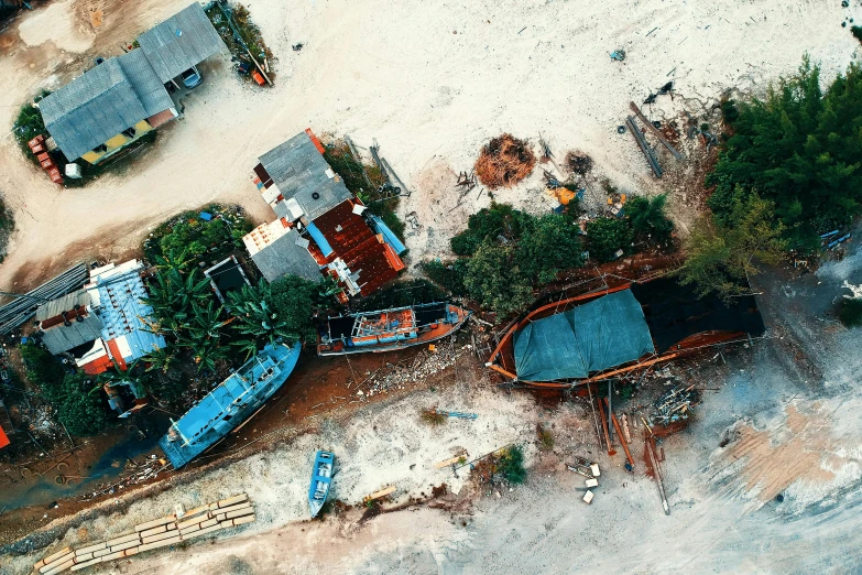 a group of boats sitting on top of a sandy beach, unsplash contest winner, photorealism, scrapyard architecture, view from the sky, malaysian, tools and junk on the ground