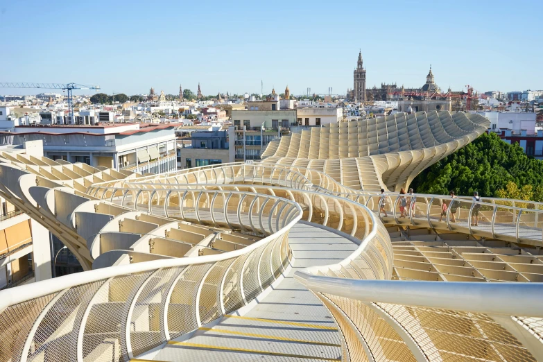 a view of a city from the top of a building, inspired by Ceferí Olivé, art nouveau, golden curve structure, seville, sustainable materials, boardwalk