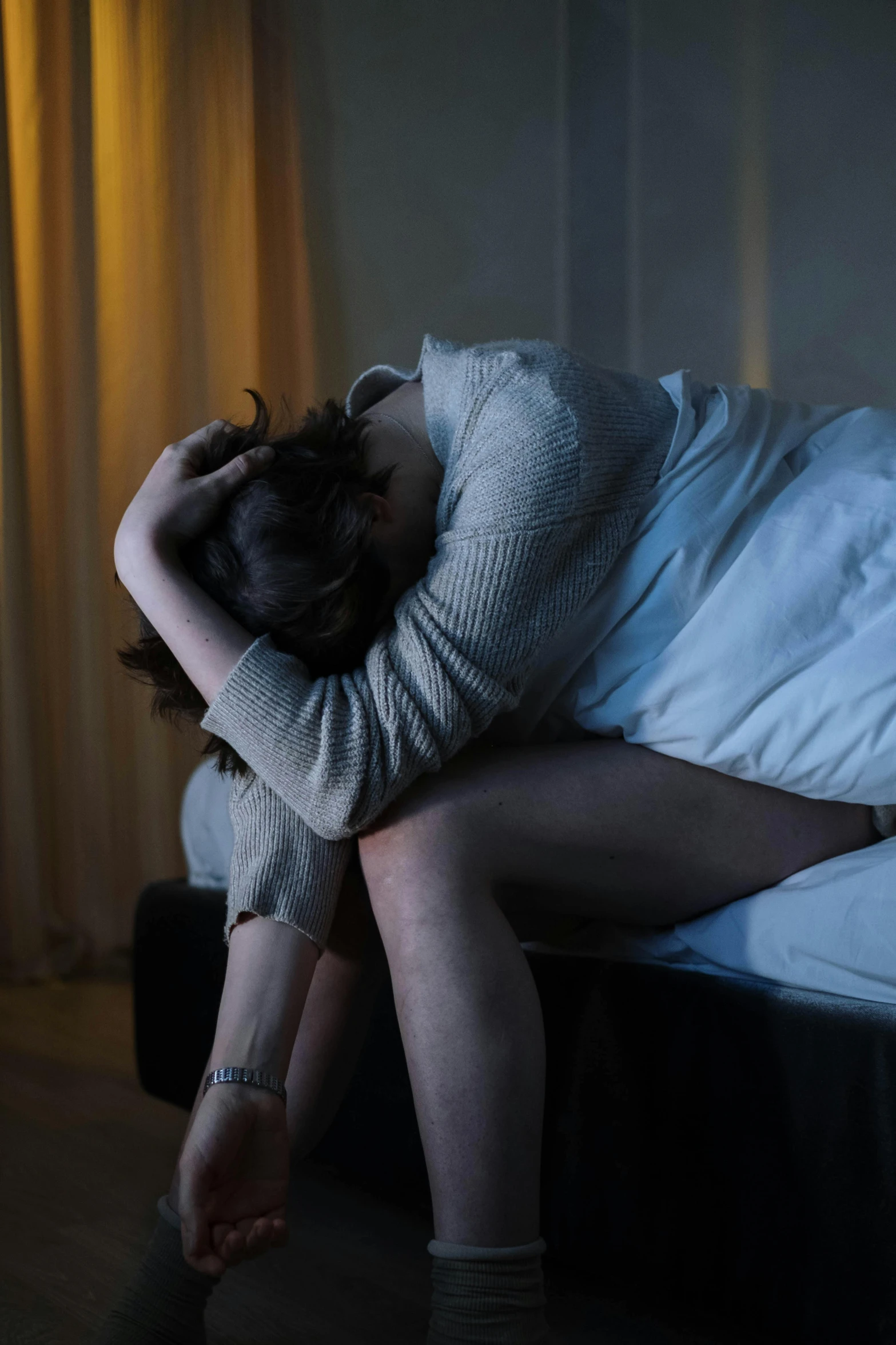 a woman sitting on a bed with her head in her hands, trending on reddit, violence, getty images, hugging her knees, paul barson