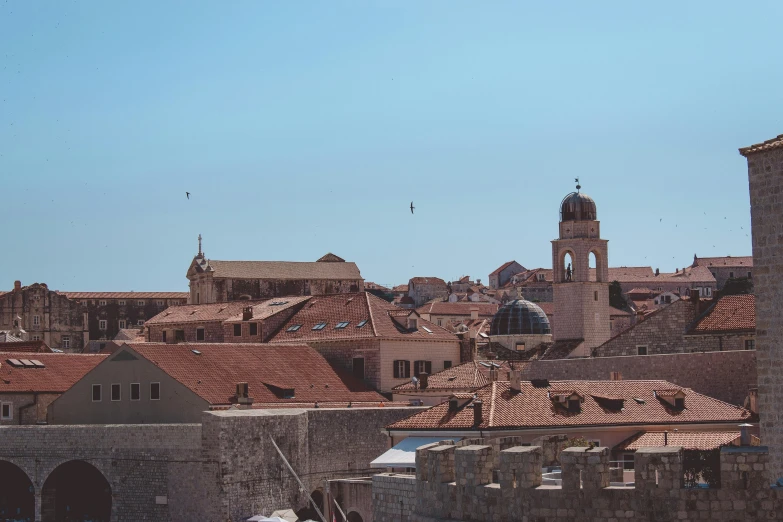 a couple of boats that are in the water, by Emma Andijewska, pexels contest winner, baroque, white buildings with red roofs, skyline view from a rooftop, clear blue skies, stone roof