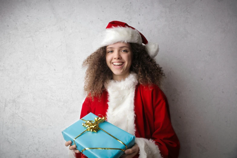 a woman in a santa suit holding a blue present, pexels contest winner, curly haired, teenage girl, avatar image, girl wearing uniform