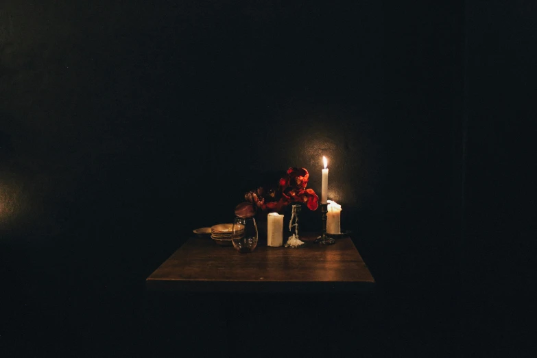 a couple of candles sitting on top of a wooden table, inspired by Elsa Bleda, vanitas, in an empty black room, dark flowers, instagram photo, unrequited love