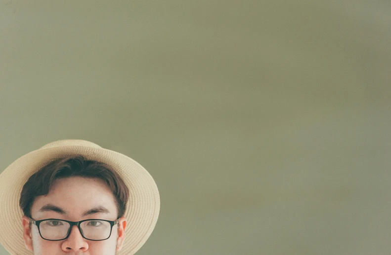 a man wearing a white hat and glasses, pexels contest winner, muted green, background image, male ulzzang, wearing straw hat