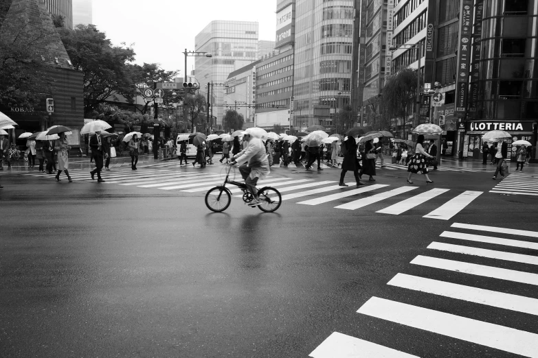 a group of people crossing a street with umbrellas, a black and white photo, by Tadashige Ono, pexels contest winner, riding a bike, deserted shinjuku junk, biker, single person with umbrella