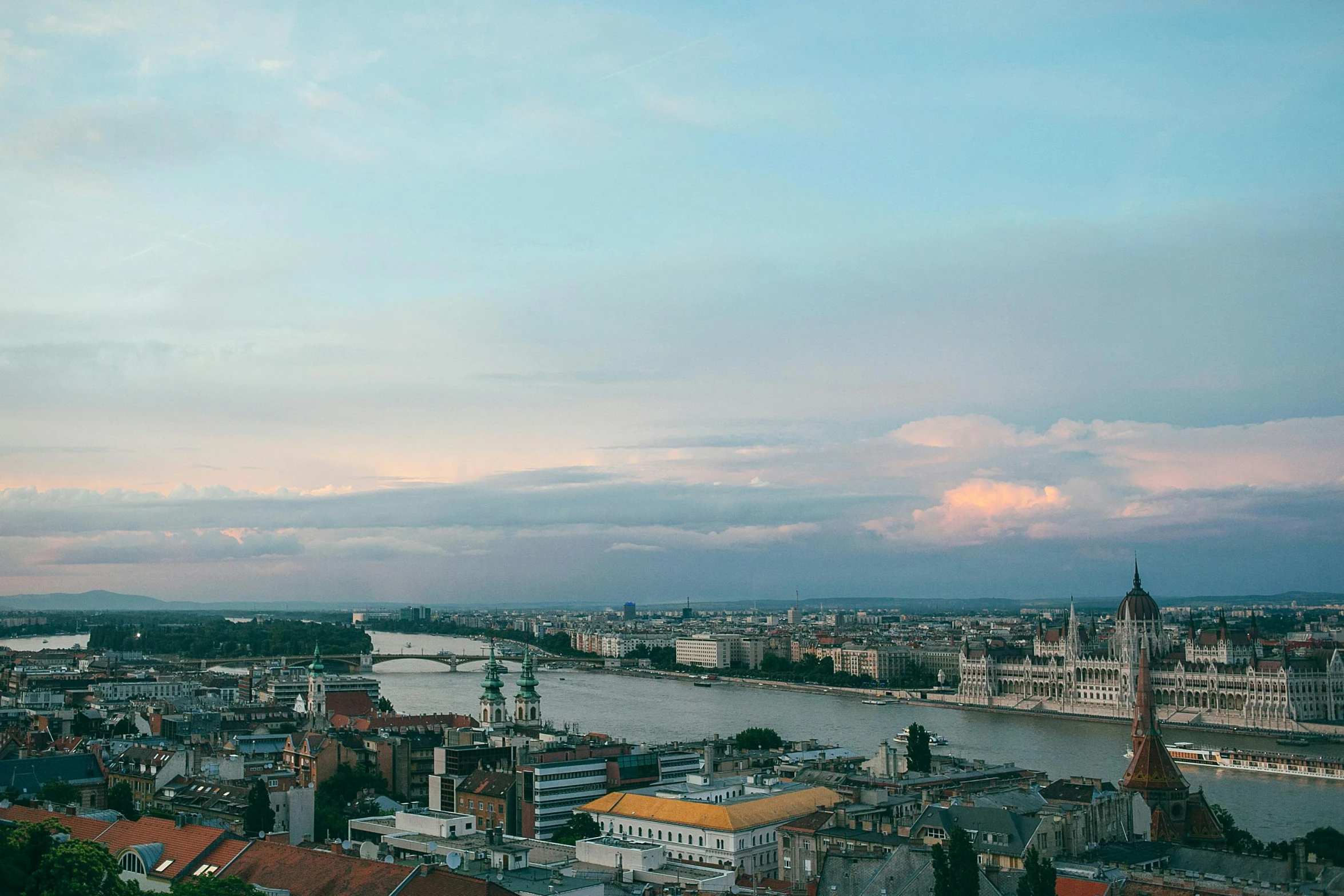 a view of a city from the top of a building, by Emma Andijewska, pexels contest winner, happening, hungarian, summer evening, & a river, slide show