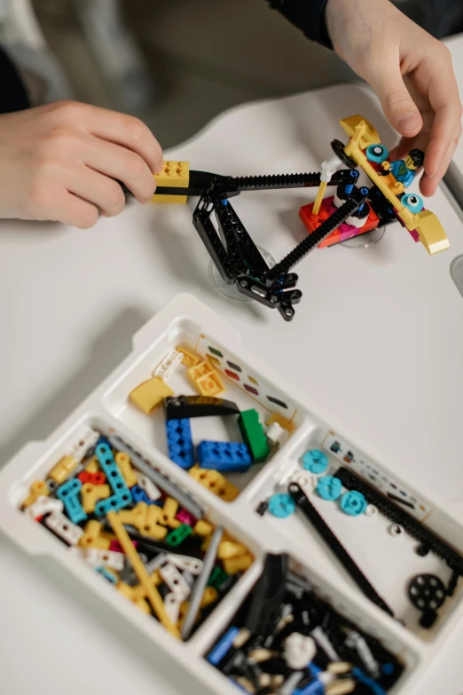 a child is playing with legos on a table, inspired by Rube Goldberg, pexels contest winner, process art, robotic arms, white wall coloured workshop, thumbnail, inspect in inventory image