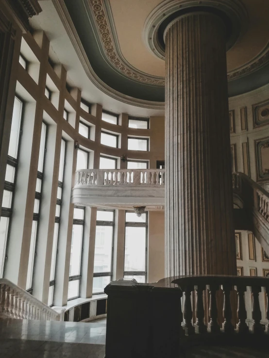 a staircase in a large building with lots of windows, unsplash contest winner, neoclassicism, background image, huge greek columns, low quality photo, dusty library