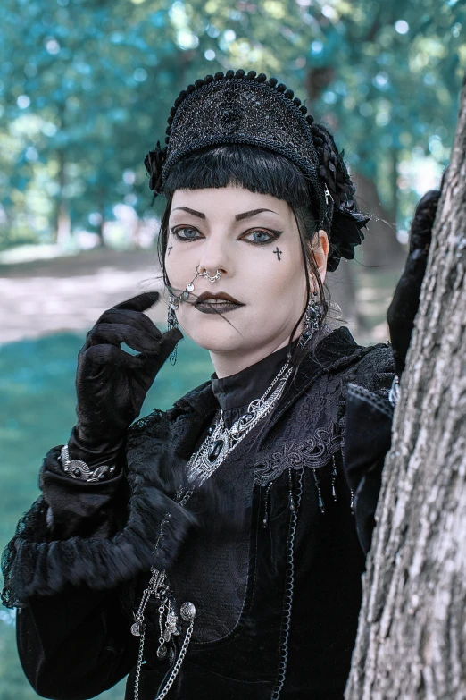 a woman dressed in black standing next to a tree, inspired by Louis Grell, gothic art, wearing spikes and piercings, photograph taken in 2 0 2 0, closeup portrait of an artificer, wearing victorian clothes