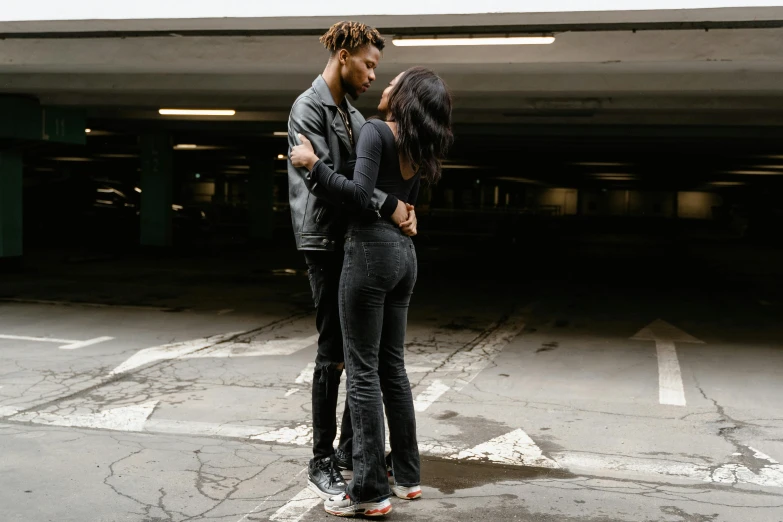 a man standing next to a woman in a parking garage, by Everett Warner, pexels contest winner, black extremely tight jeans, kissing together cutely, ashteroth, standing in road