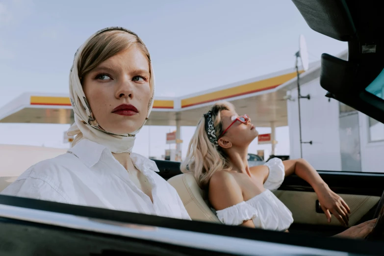 two women sitting in a car at a gas station, an album cover, trending on pexels, wearing white silk, eleven/millie bobbie brown, conde nast traveler photo, neck up