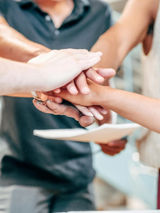 a group of people putting their hands together, by Carey Morris, trending on unsplash, holding a white duck, people at work, holding a staff, background image