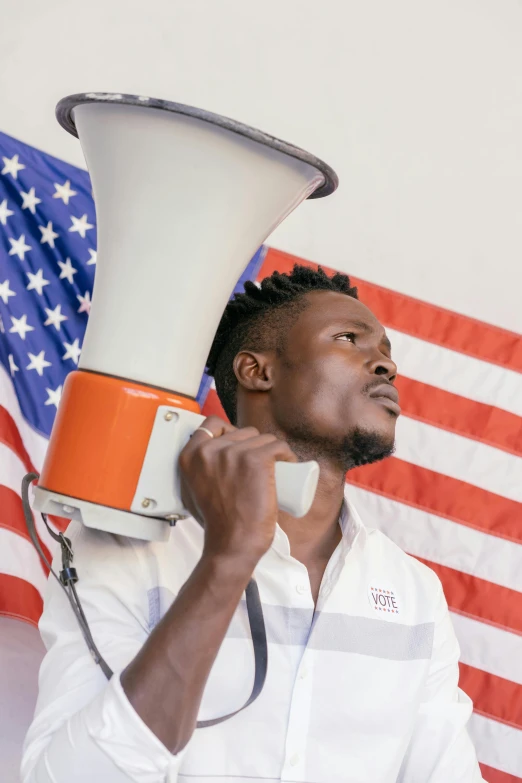 a man holding a megaphone in front of an american flag, trending on unsplash, black arts movement, adut akech, profile picture, multiple stories, lgbtq