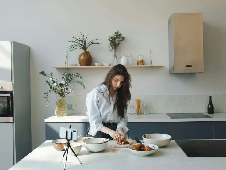 a woman standing in a kitchen preparing food, inspired by Lucia Peka, trending on pexels, minimalism, on kitchen table, girl in studio, angled, presenting wares