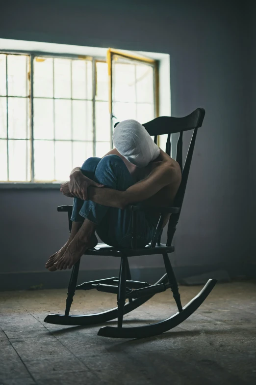 a man sitting in a rocking chair in front of a window, pexels contest winner, balaclava covering face, abused, studio shot, joel fletcher