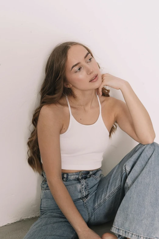 a woman sitting on the floor in a white tank top, inspired by Károly Lotz, trending on pexels, wearing a crop top, wearing denim, kailee mandel, top down