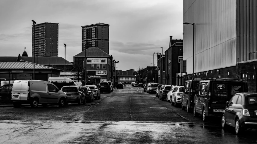 a black and white photo of a city street, a black and white photo, inspired by Thomas Struth, unsplash, on a parking lot, hull, dramatic sky, busy city