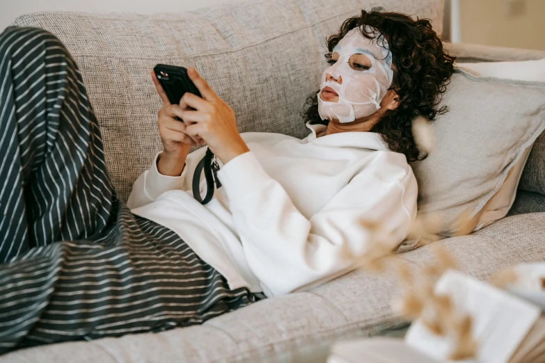 a woman laying on a couch using a cell phone, trending on pexels, happening, masks on wires, white face makeup, attractive photo, realistic »