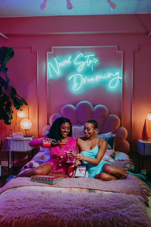 a couple of women sitting on top of a bed, an album cover, trending on pexels, happening, bright neon signs, sweet dreams, official store photo, promotional image