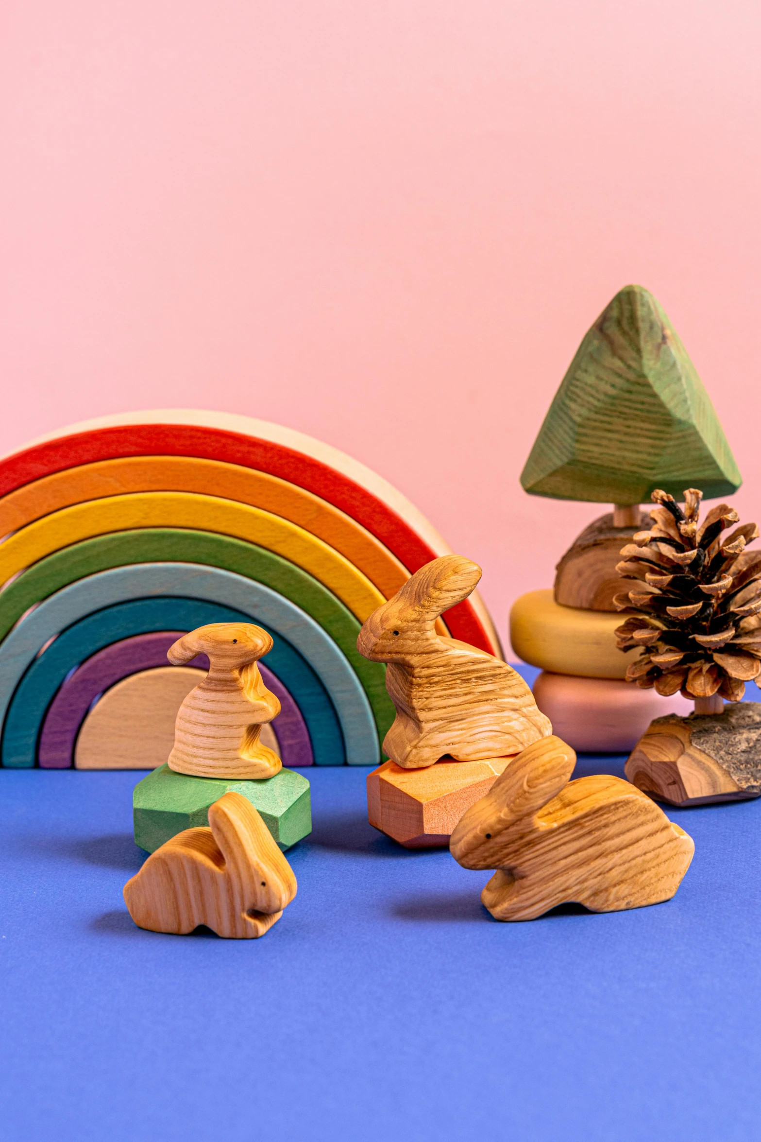 a group of wooden toys sitting on top of a blue surface, inspired by Okuda Gensō, a forest with bunnies, botanical rainbow backdrop, thumbnail, pine