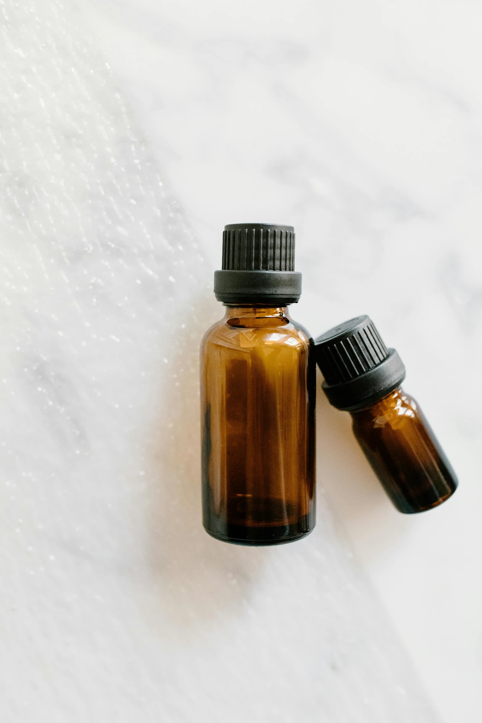 a bottle of essential oil next to a small bottle of essential oil, unsplash, plain background, brown, jen atkin, low detail