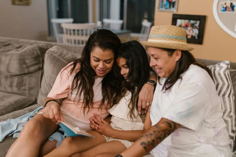 a couple of women sitting on top of a couch, pexels contest winner, happening, portrait of family of three, snapchat photo, lesbian, using a magical tablet