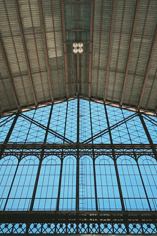 a clock hanging from the ceiling of a train station, inspired by Luis Paret y Alcazar, simple gable roofs, aquamarine windows, laquer and steel, huge greenhouse