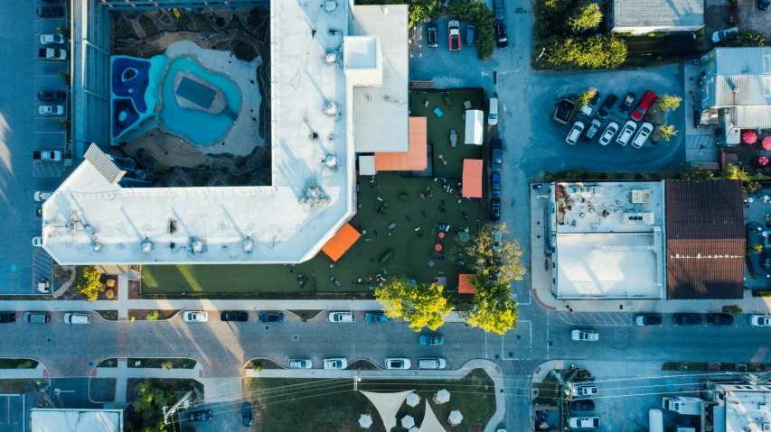 an aerial view of a parking lot with cars, by Andrew Stevovich, unsplash contest winner, realism, rooftop party, square, schools, orange roof