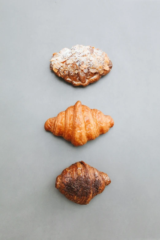 a group of croissants sitting on top of a table, on a gray background, ffffound, the three moiras, top down angle