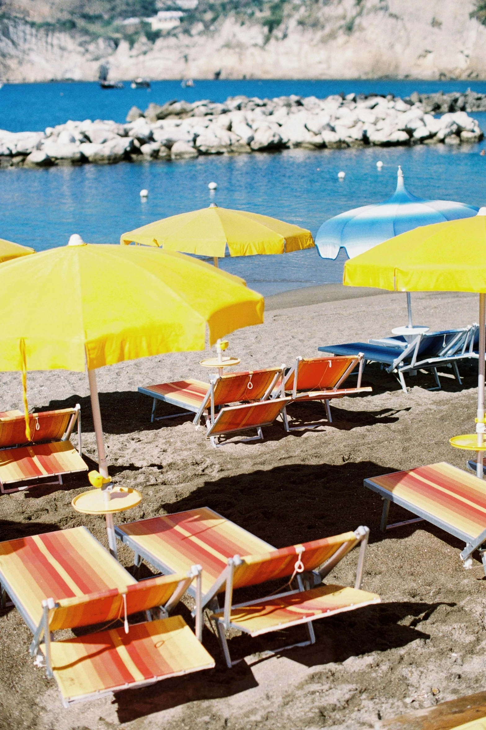 a bunch of beach chairs and umbrellas on a beach, by Giorgio De Vincenzi, scarlet and yellow scheme, monaco, in a sun lounger, bay