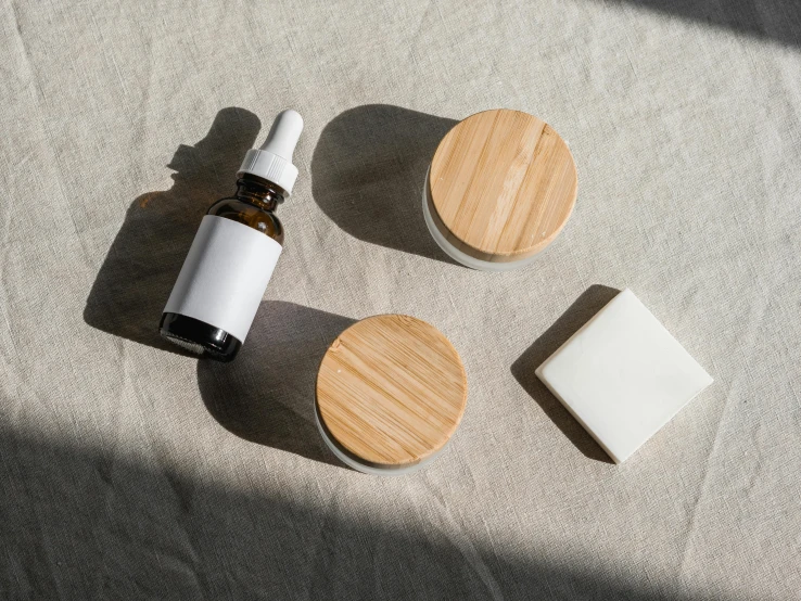 a bottle of essential oil sitting on top of a table, a still life, unsplash, random circular platforms, white powder makeup, made of bamboo, product view