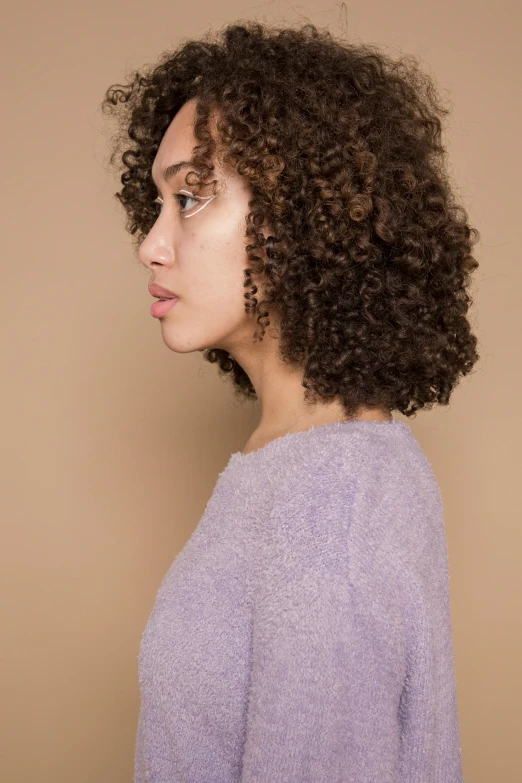 a woman with curly hair wearing a purple sweater, trending on pexels, from side, light-brown skin, plain background, highly detailed image