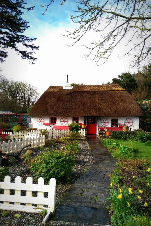 a small white house with a thatched roof, an album cover, inspired by Mór Than, pexels contest winner, in red gardens, tourist destination, exterior view, cosy