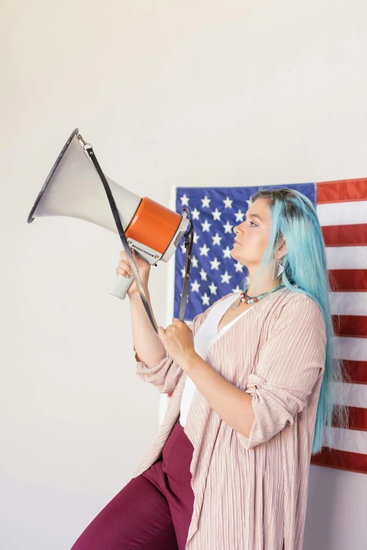 a woman with blue hair holding a megaphone in front of an american flag, a colorized photo, trending on reddit, long orange hair floating on air, profile picture 1024px, subreddit / r / whale, larynx