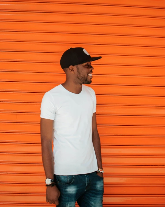 a man standing in front of an orange garage door, by Quinton Hoover, dressed in a white t shirt, dark black skin tone, highly upvoted, profile image