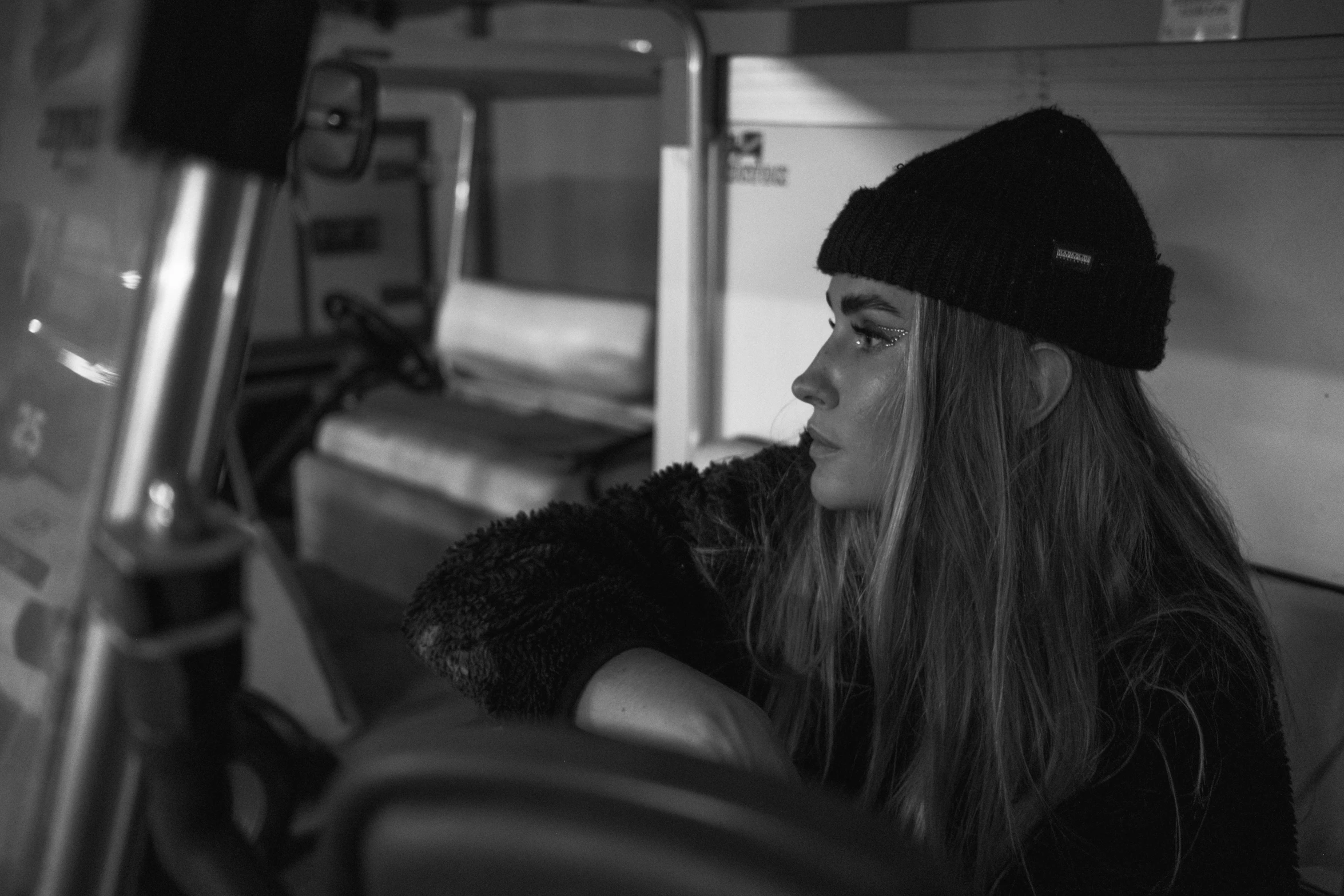 a black and white photo of a woman sitting in a bus, by Emma Andijewska, pexels, realism, wearing a beanie, cara delevingne, profile picture 1024px, she is wearing streetwear