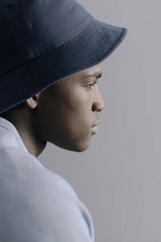 a close up of a person wearing a hat, inspired by Paul Georges, male teenager, posed in profile, promotional image, indigo