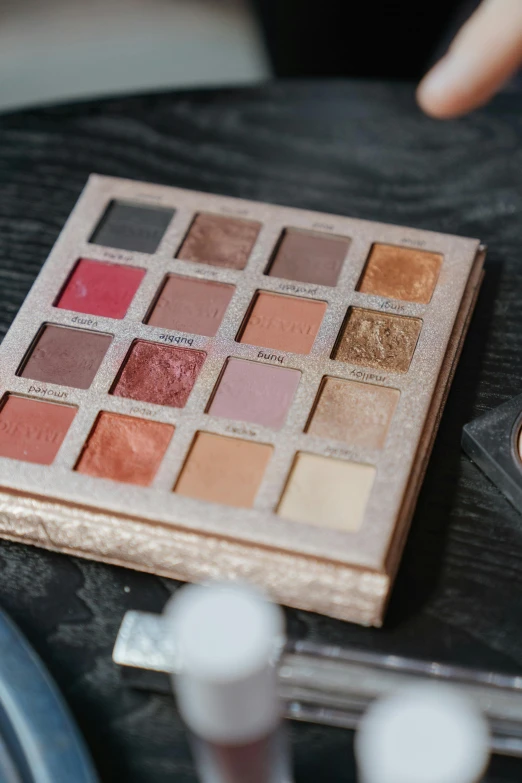 a close up of a person putting makeup on a table, a polaroid photo, trending on pexels, baroque, ochre ancient palette, cubes on table, urban decay, game ready
