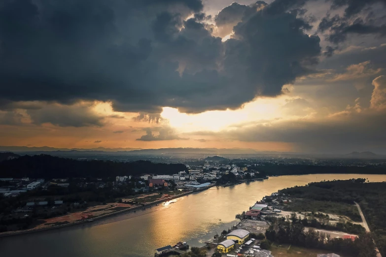 a large body of water under a cloudy sky, pexels contest winner, sun and shadow over a city, laos, drone photograpghy, evening storm