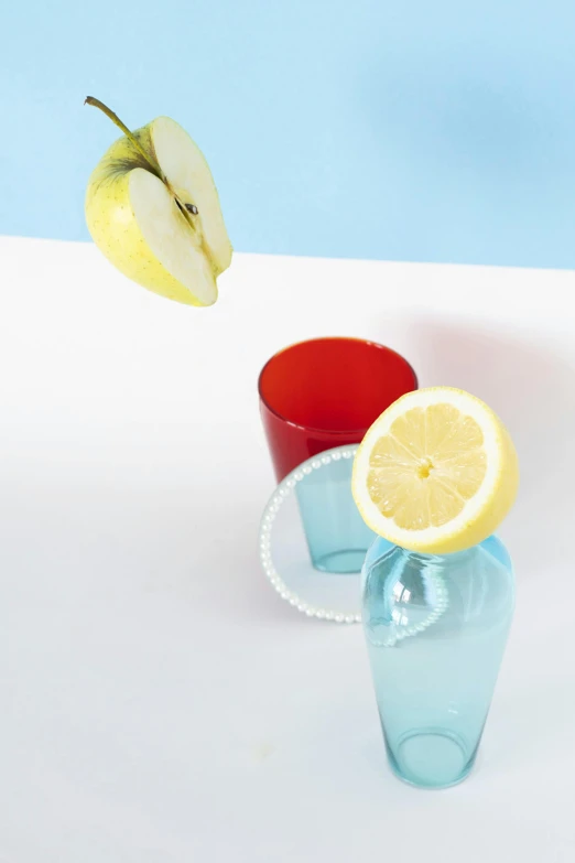 a couple of cups sitting on top of a table, a still life, by Doug Ohlson, lemonade, light-blue, apple, shot from below