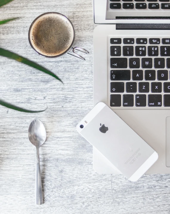 a laptop computer sitting on top of a desk next to a cup of coffee, trending on unsplash, iphone 13, grey and silver, cutlery, thumbnail