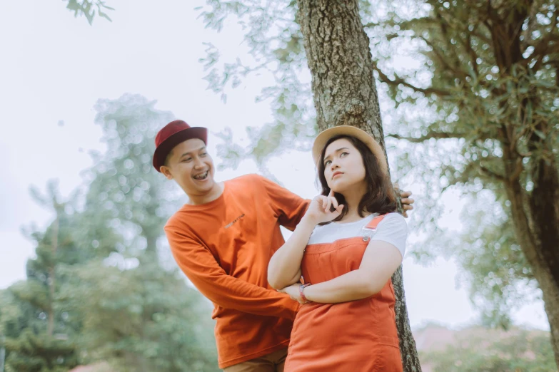 a man standing next to a woman near a tree, pexels contest winner, wearing an orange t shirt, bao phan, background image, picnic